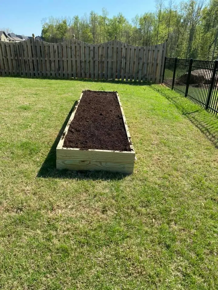 A completed timber raised garden bed on a fenced lawn in Helena, Alabama.