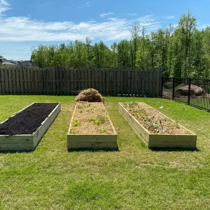 Three timber raised beds during installation on a backyard lawn.